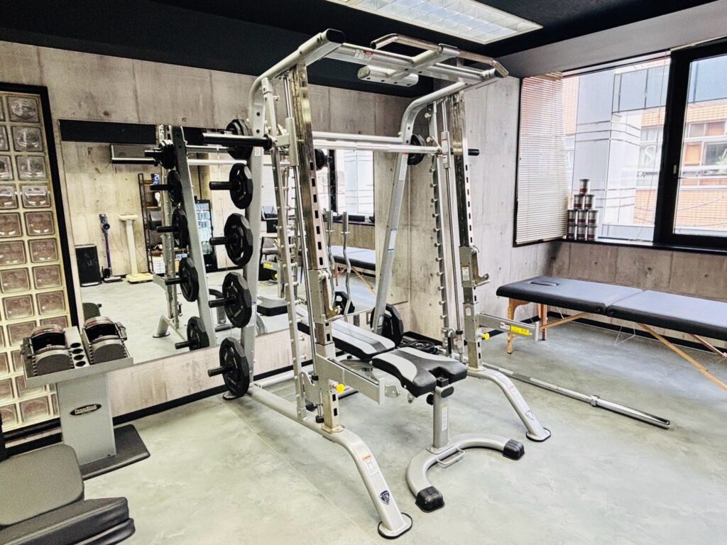 THE PERSONAL GYM柏店の窓側のトレーニング器具とベッド